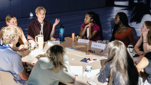 A group of CCF students, gathered at a table, engaged in conversation