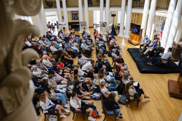 A crowd is seated in front of panelists